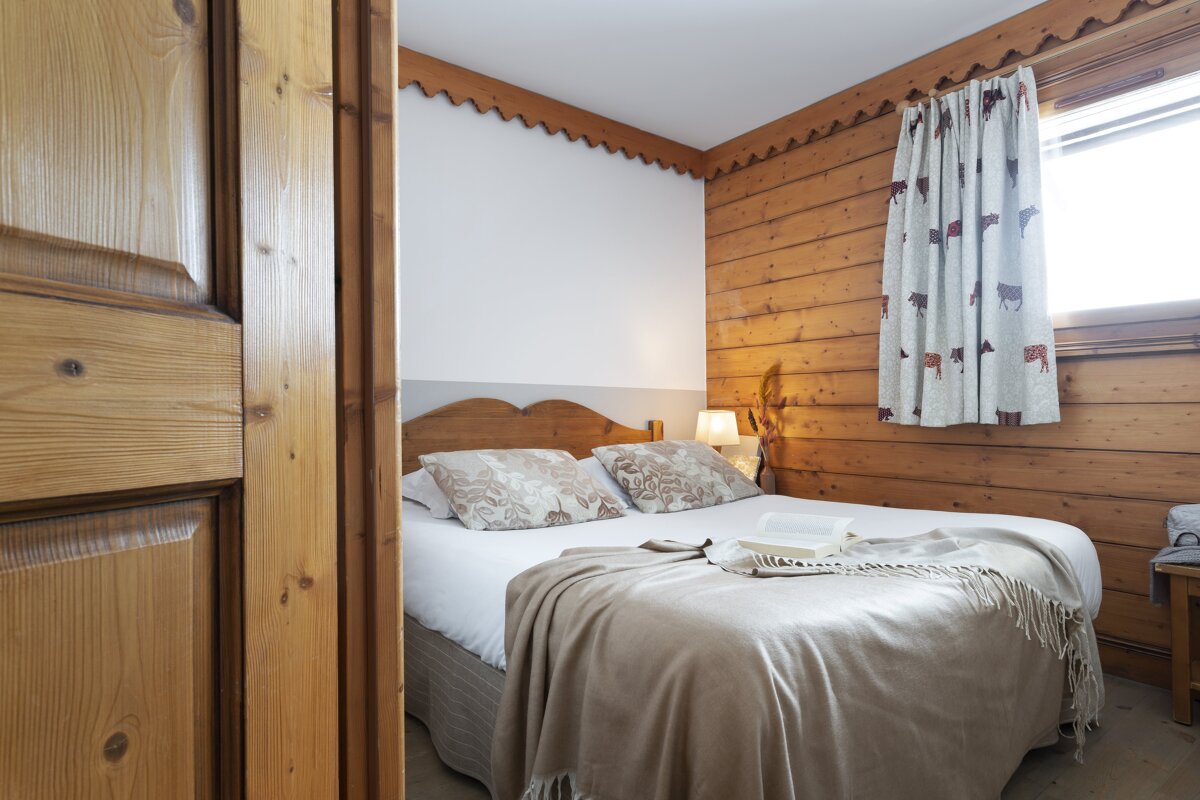 A bedroom with wood paneling and a bed with a blanket on it