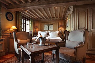A bedroom with two chairs and a table with a bottle of champagne on it