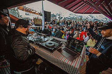 A dj playing music in front of a crowd wearing a hoodie that says ' abercrombie & fitch ' on it