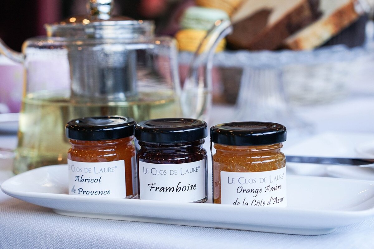 Three jars of jam from le clos de laure sit on a white plate