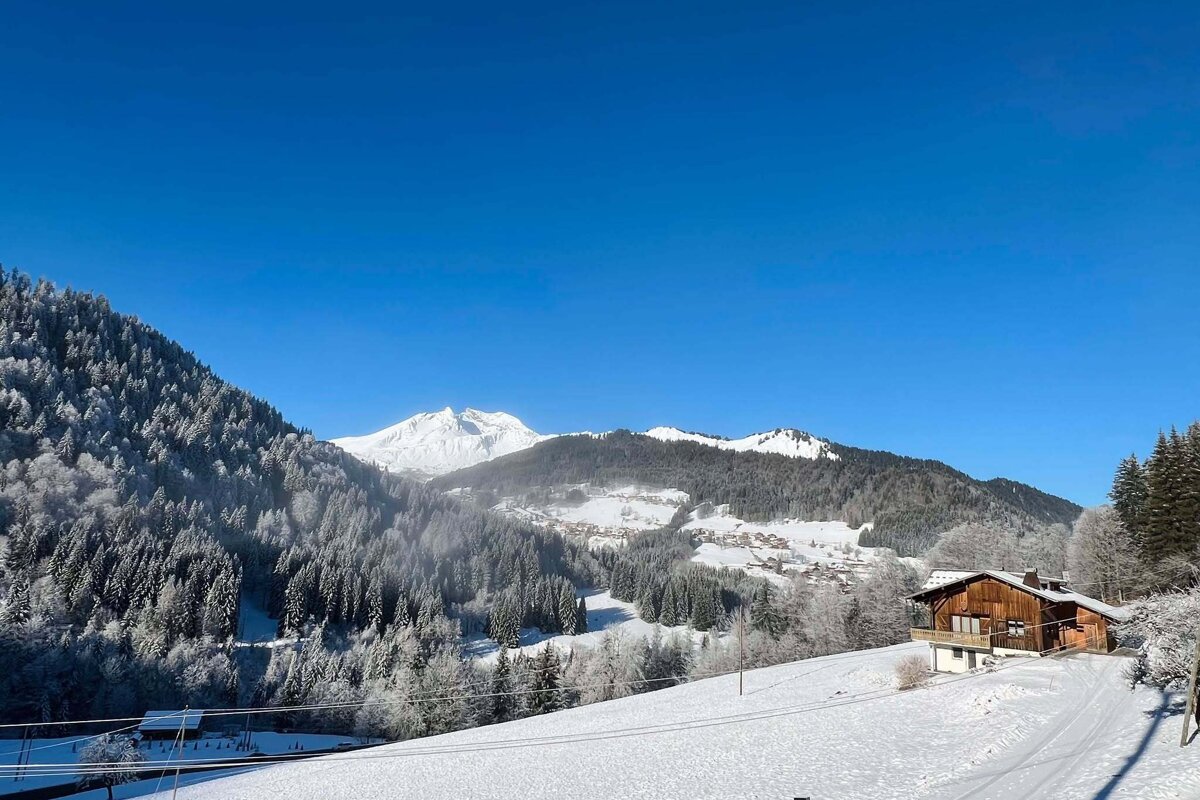 A snowy mountain landscape with a house in the foreground