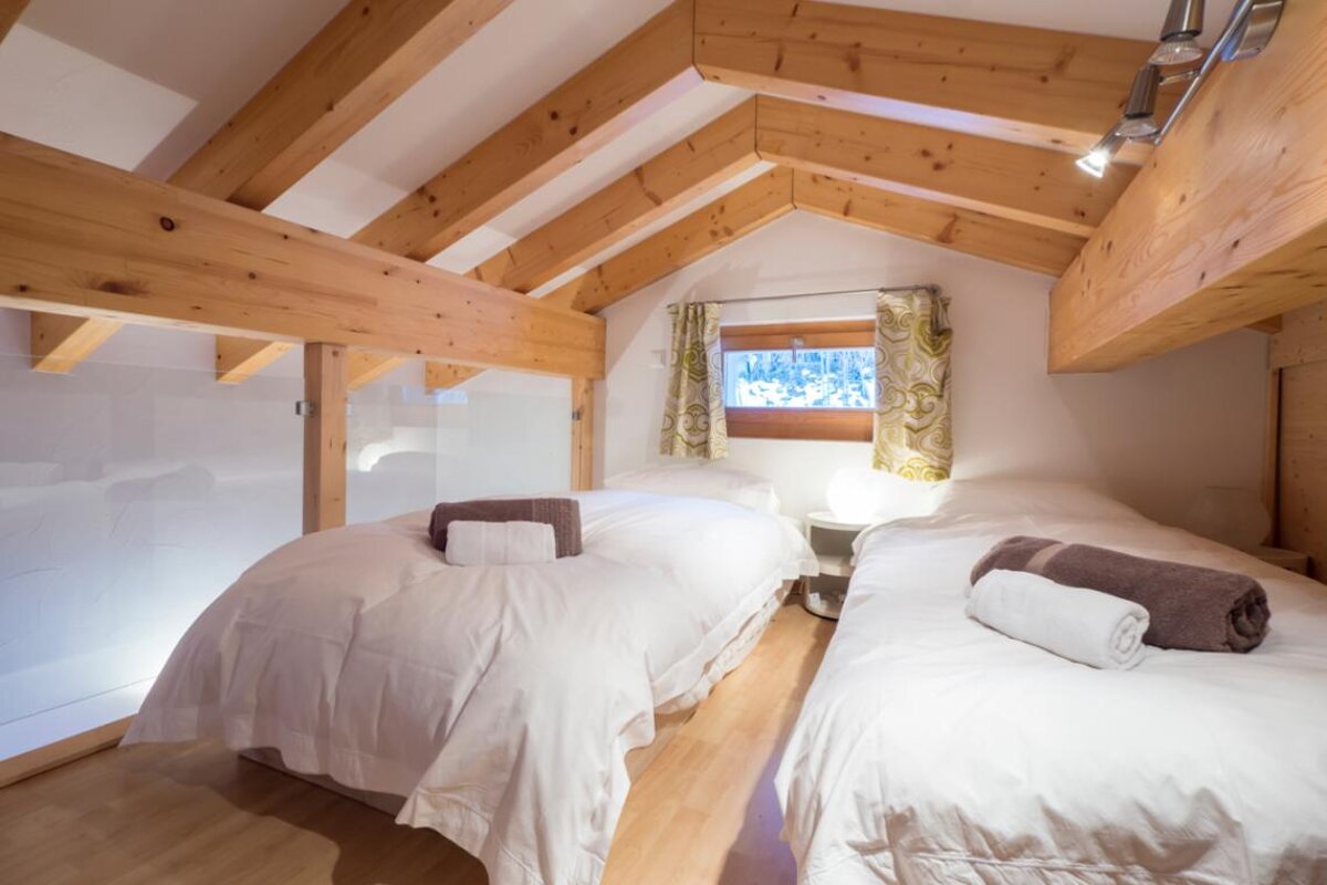 A bedroom with two beds under a wooden ceiling