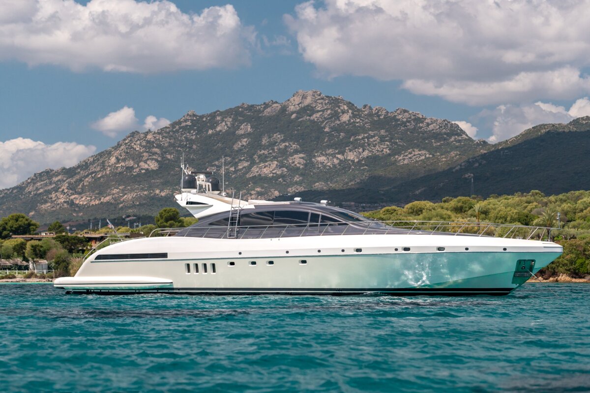 A large yacht is floating in the ocean with a mountain in the background