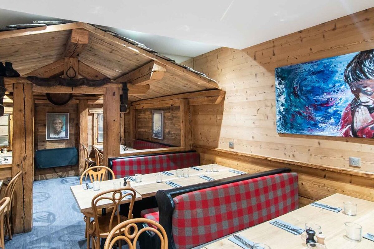 A dining room with tables and chairs and a painting on the wall