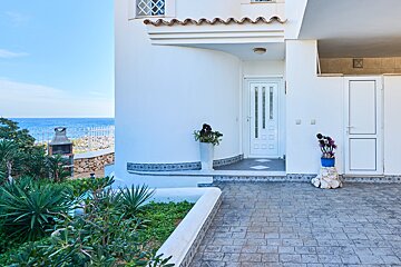 A white house with a blue potted plant in front of it