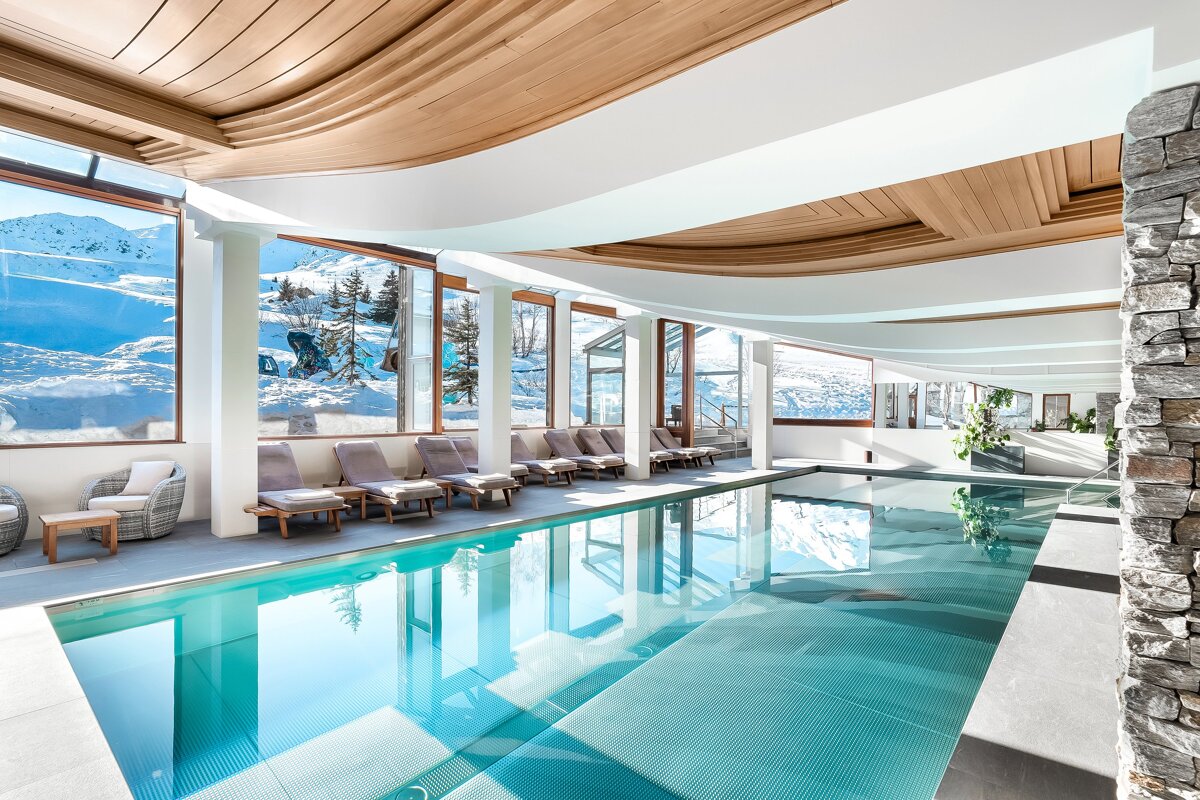 A large indoor swimming pool with chairs and a ski lift in the background