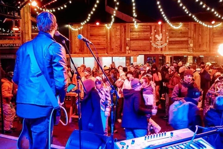 A man singing into a microphone in front of a crowd with a sign that says