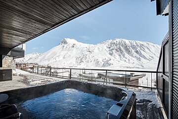 A hot tub on a balcony overlooking a snowy mountain