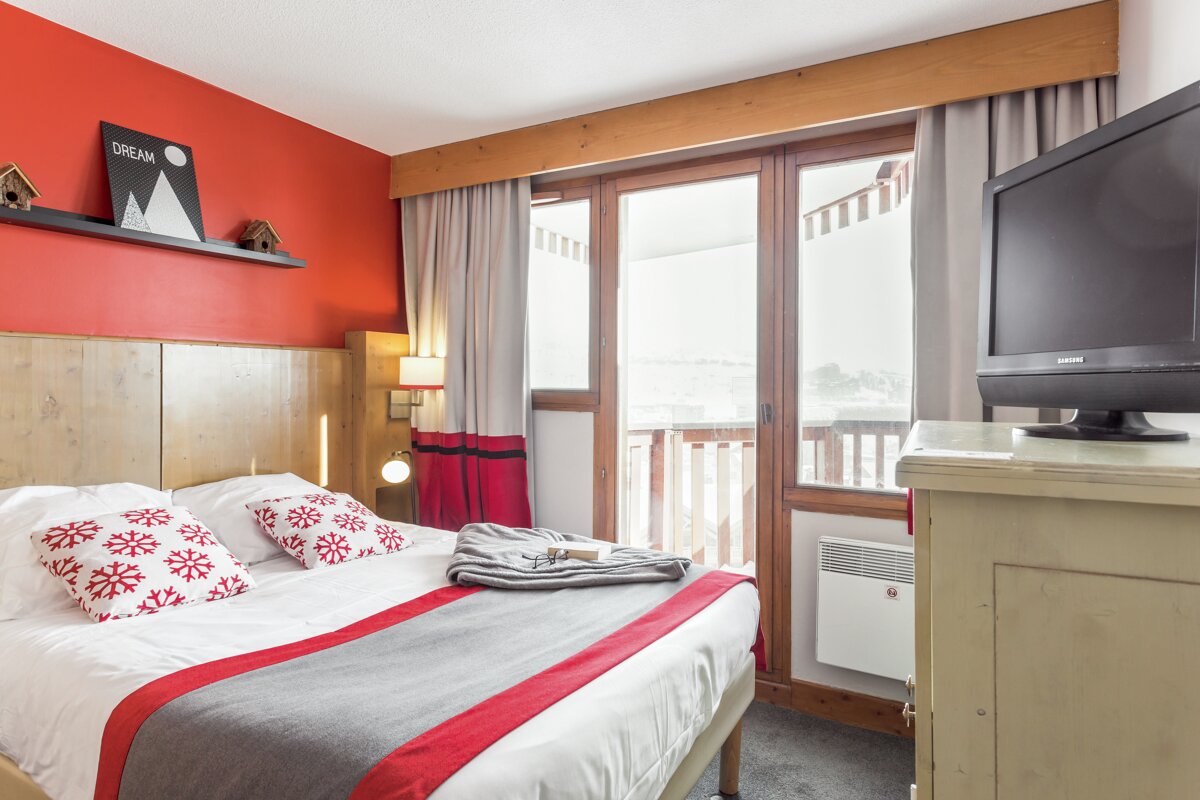 A hotel room with a large bed and a television