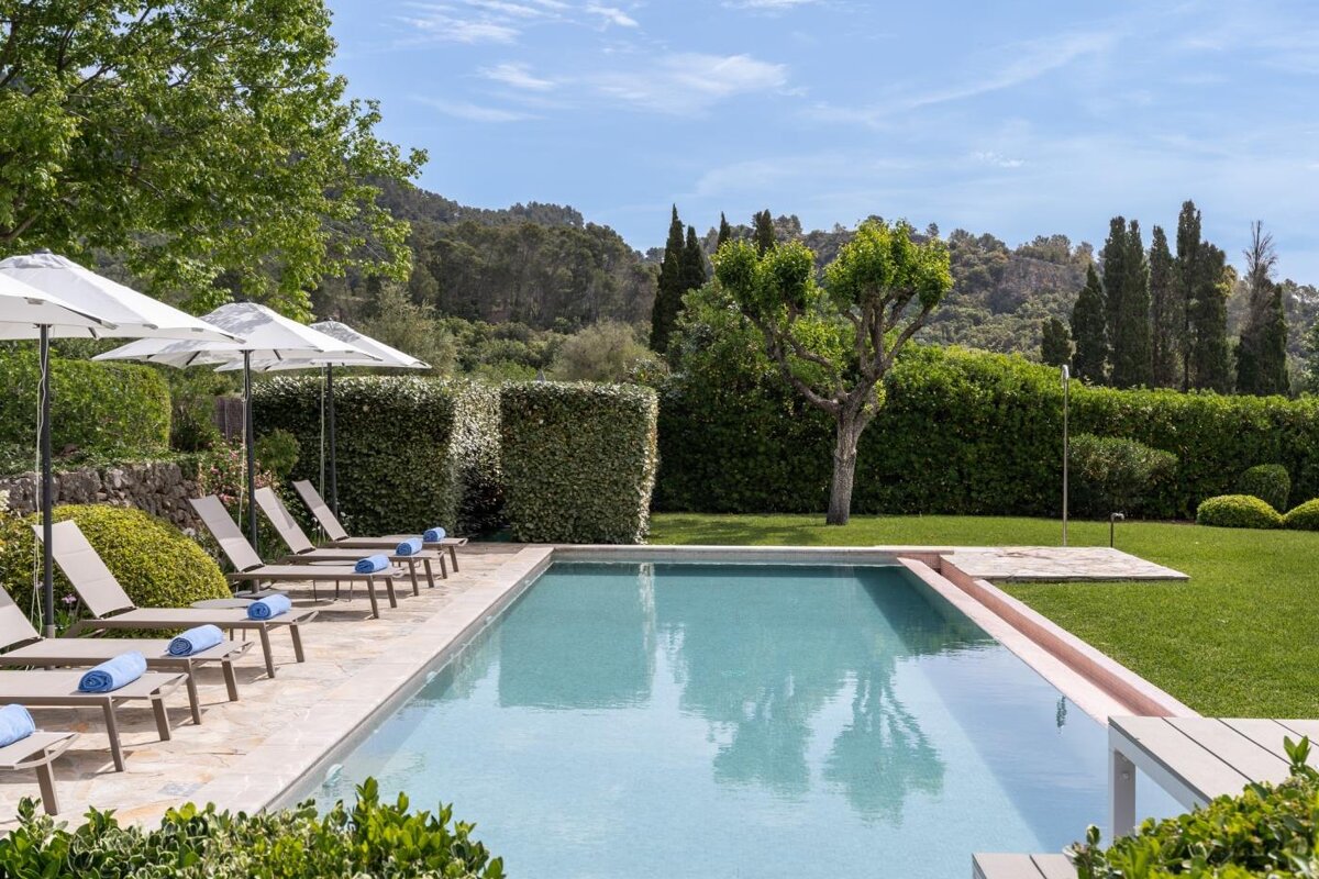 A large swimming pool surrounded by chairs and umbrellas