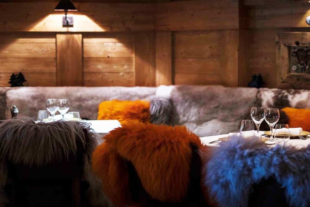 A dining room with a couch covered in fur and glasses on the table