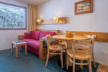 A living room with a red couch and a wooden table