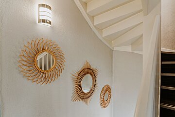 A spiral staircase with three mirrors on the wall