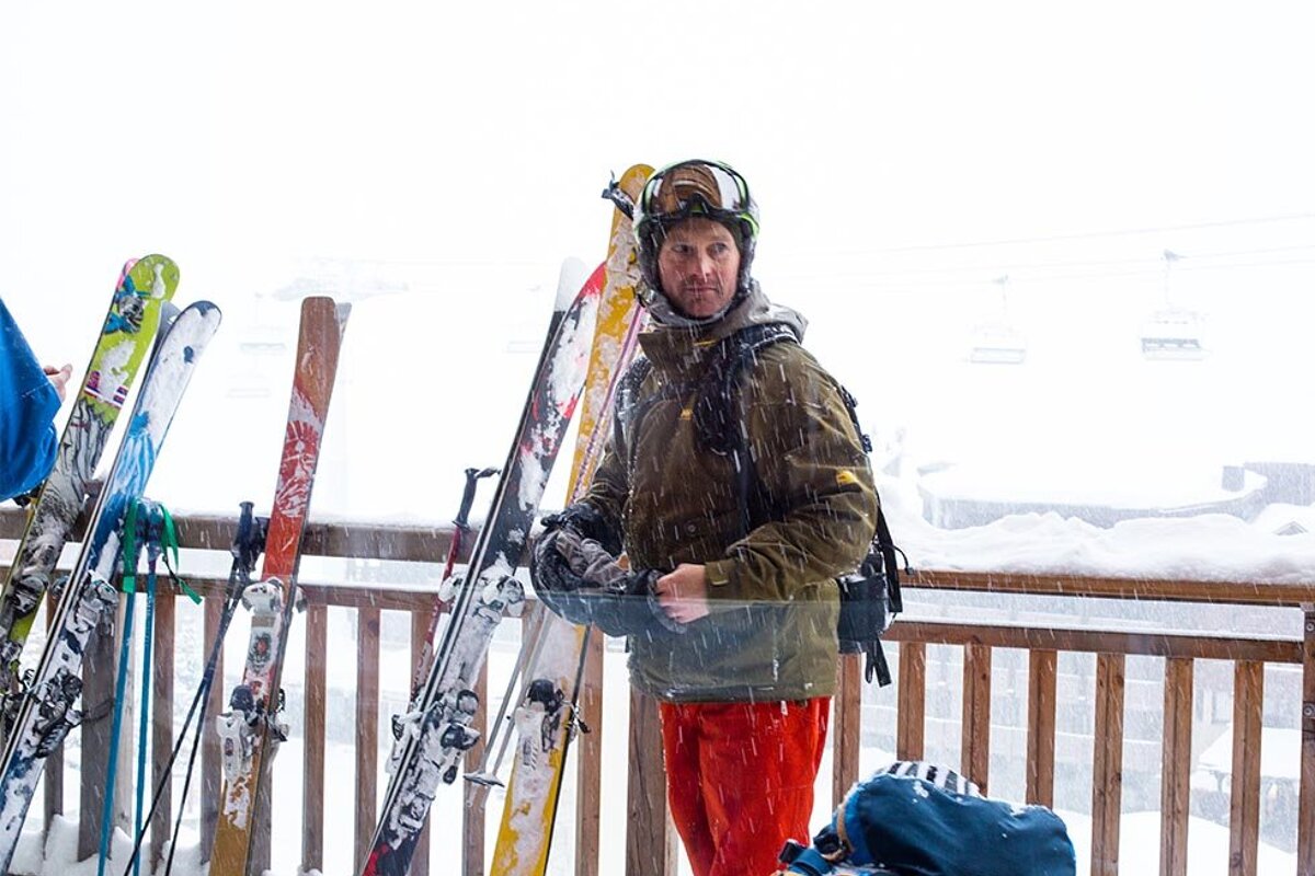 A man wearing a salomon backpack is standing in the snow