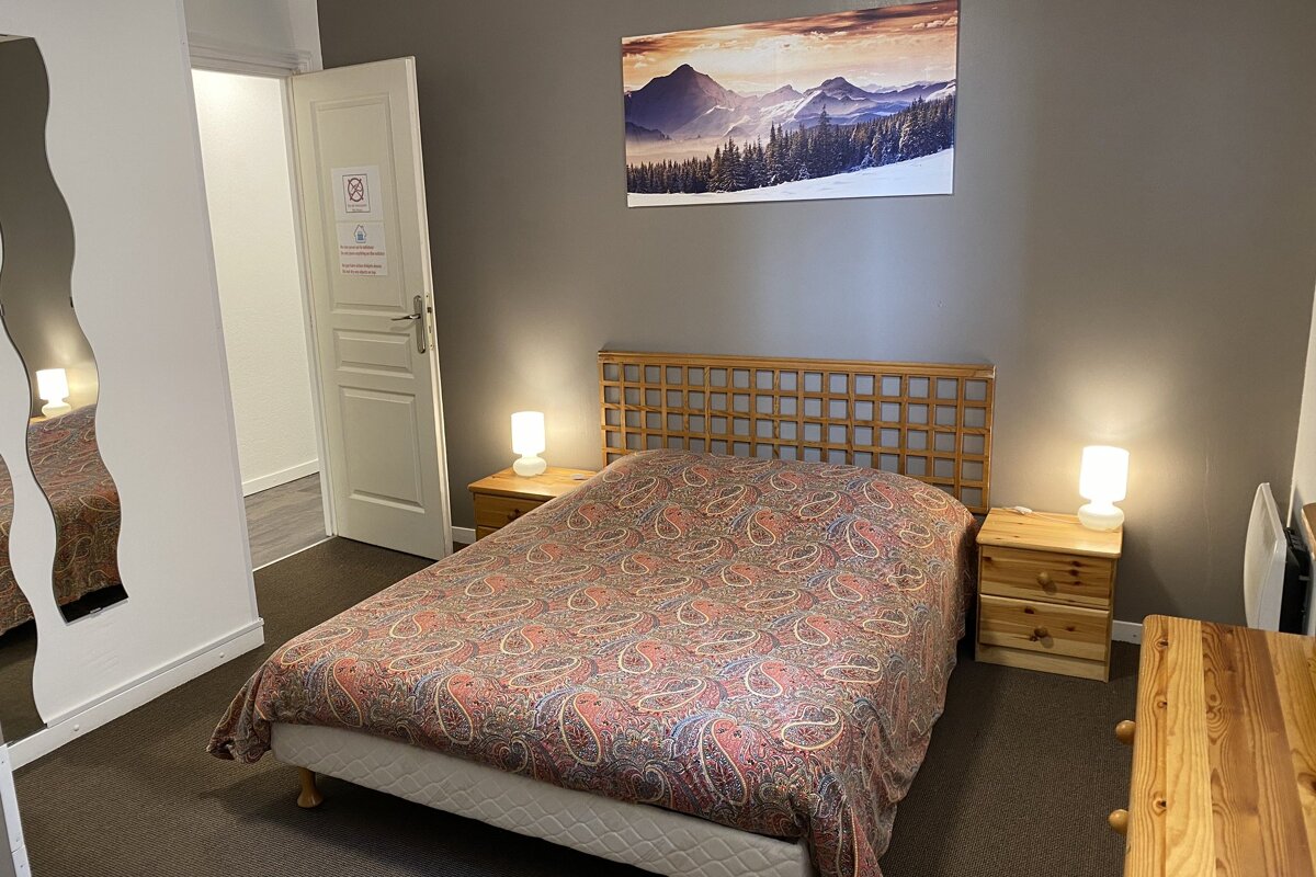 A bedroom with a painting of mountains on the wall above the bed