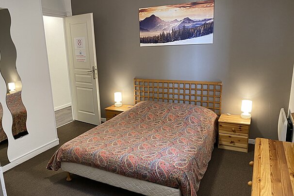 A bedroom with a painting of mountains on the wall above the bed