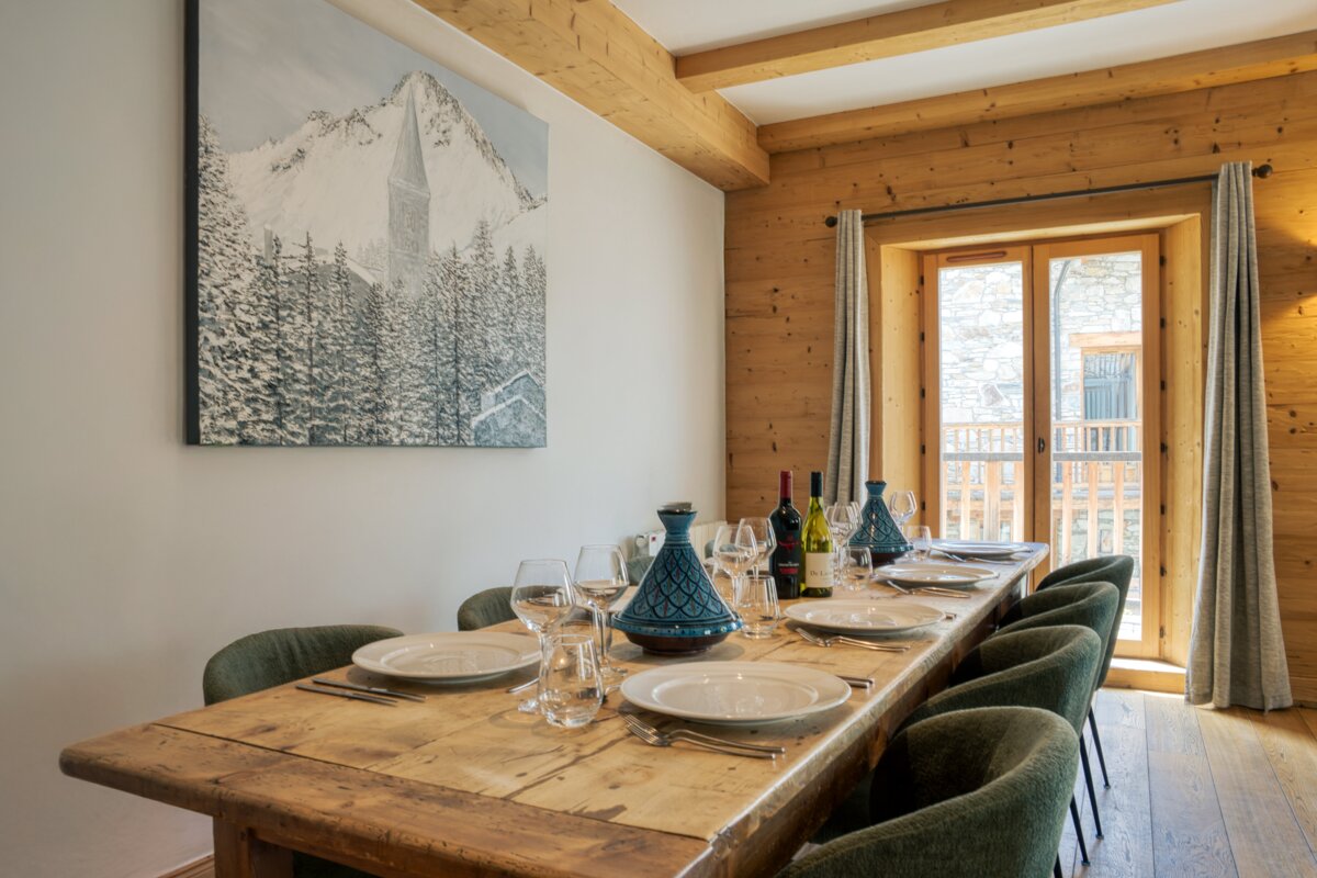 A dining room table with plates glasses and bottles of wine