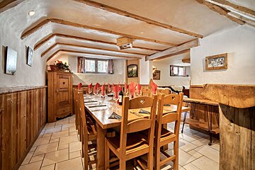 A dining room with a long wooden table and chairs