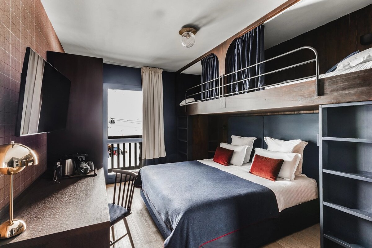 A hotel room with a bunk bed and a desk