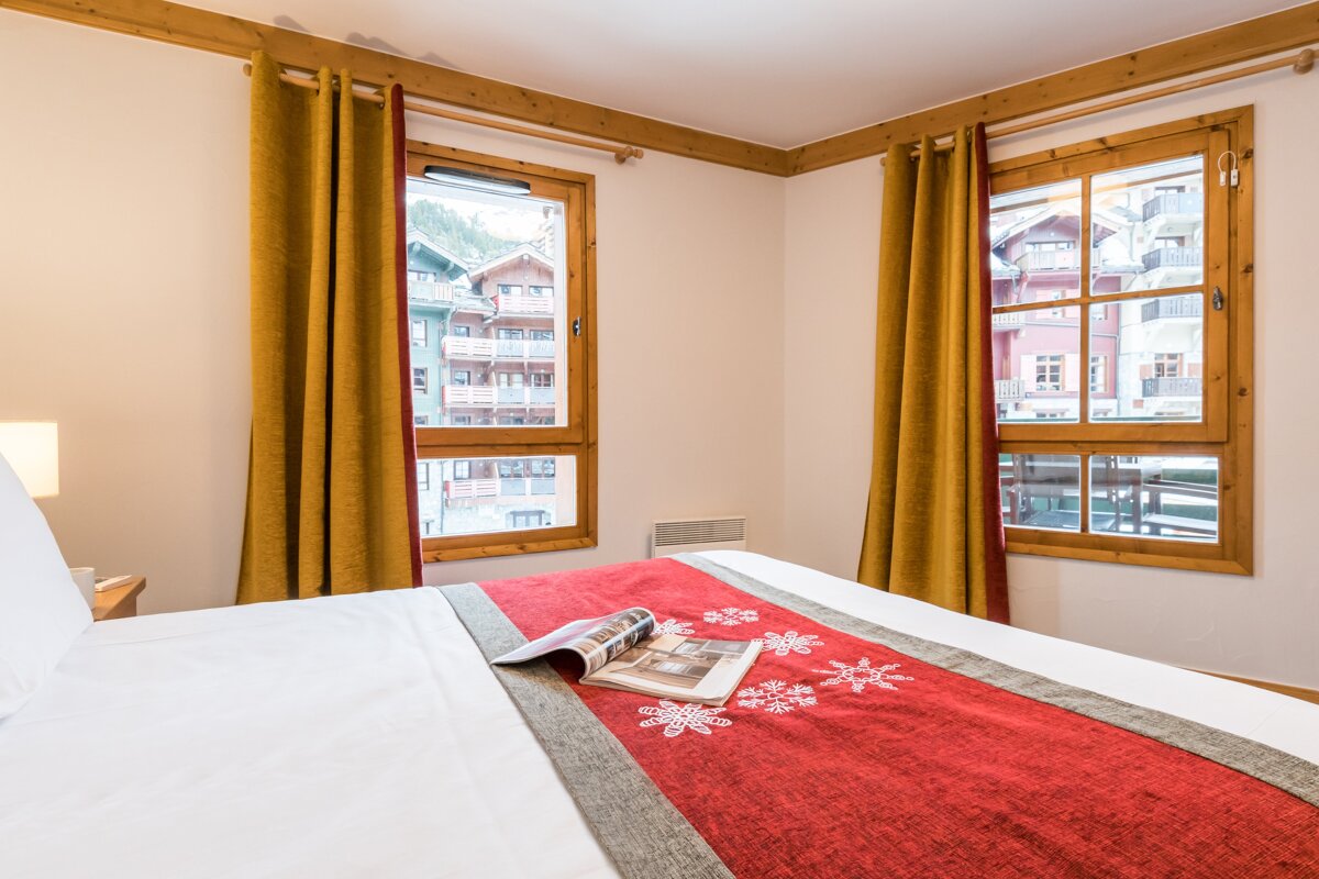 A bed with a red blanket and a magazine on it