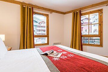 A bed with a red blanket and a magazine on it