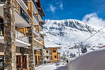 A snowy mountain behind a building that says ' l' ermitage ' on it
