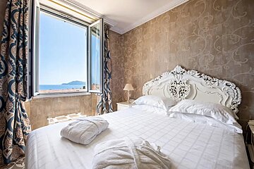 A bedroom with a bed and a window with a view of the ocean