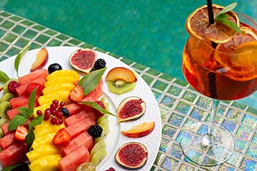 A plate of fruit next to a glass of drink