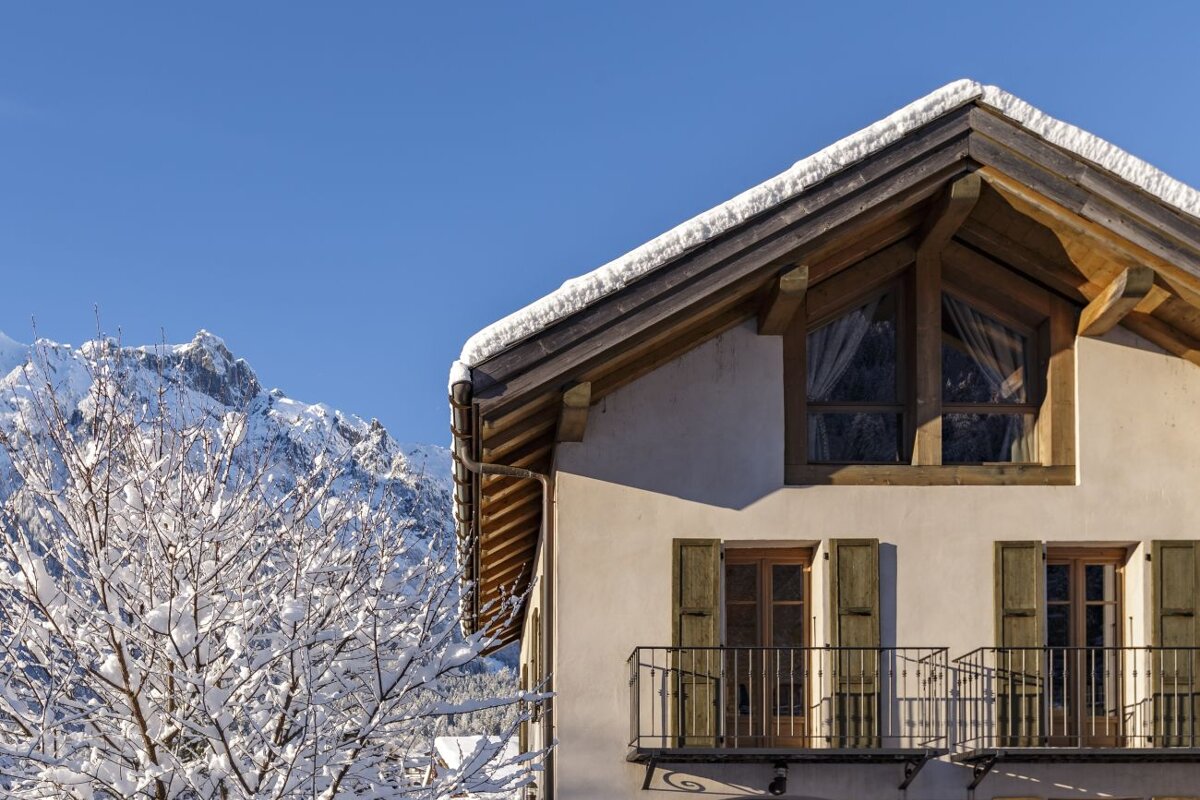 A house with snow on the roof and mountains in the background