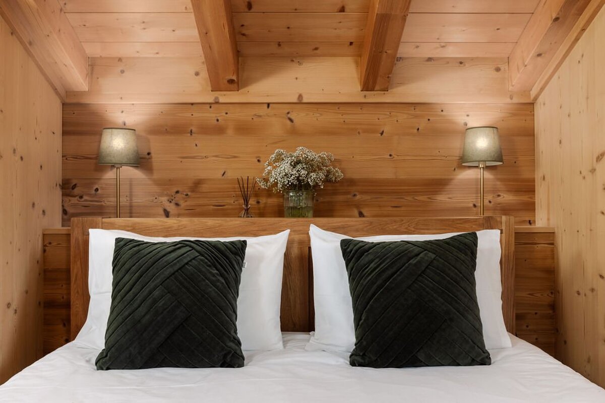A bed with green pillows and a vase of flowers on the headboard