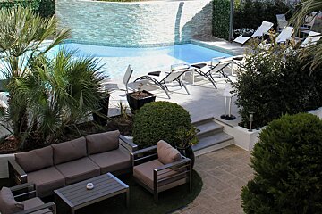 A patio with a couch and chairs next to a pool