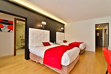 A hotel room with two beds and a painting on the wall