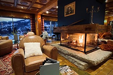 A leather chair sits in front of a fireplace with a magazine on the floor that says