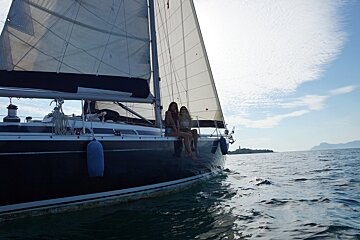 Two women sit on a sailboat in the ocean