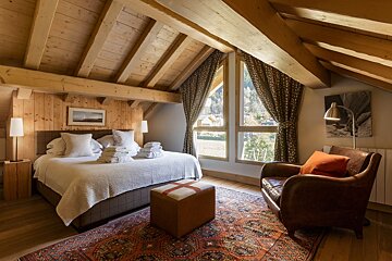 A bedroom with a large bed and a chair