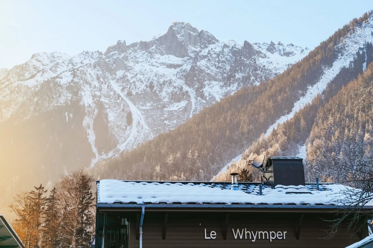 A snowy mountain behind a building that says le whymper