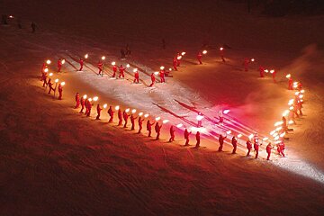 French ski school teachers making a heart out of torches in the snow in Les Gets
