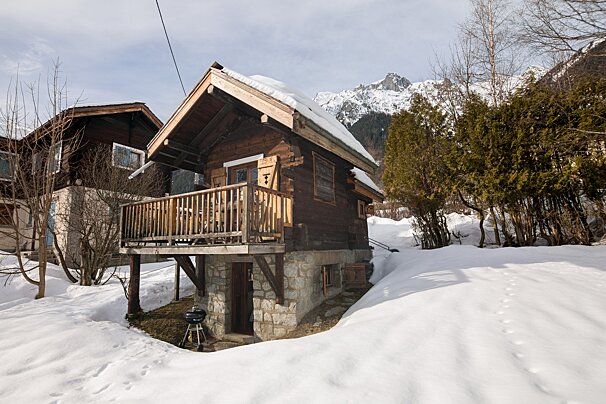 A small cabin in the snow with a mountain in the background