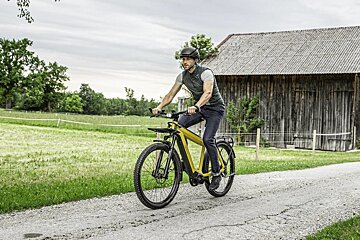 A man wearing a helmet is riding a bike on a dirt road