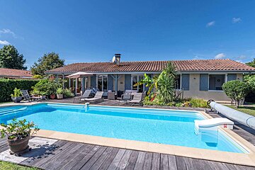 A house with a large swimming pool in front of it