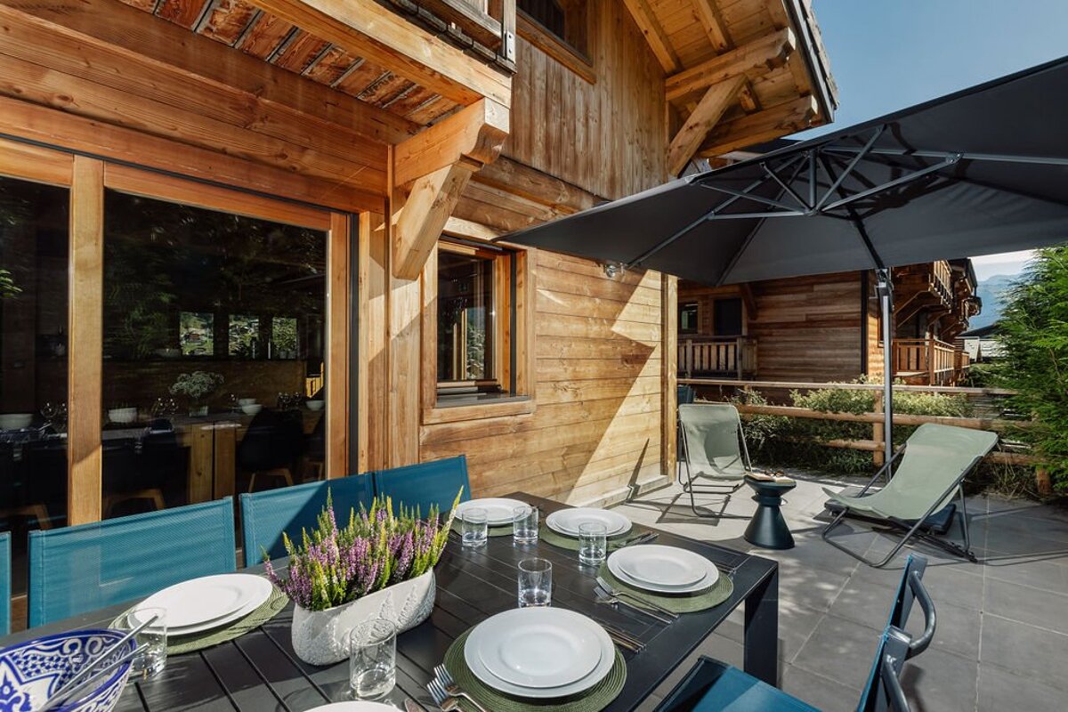 A table set with plates and umbrellas in front of a wooden building