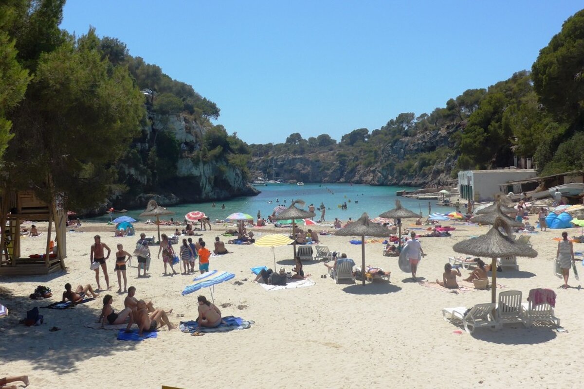 lots of parasols and people sunbathing on the beach