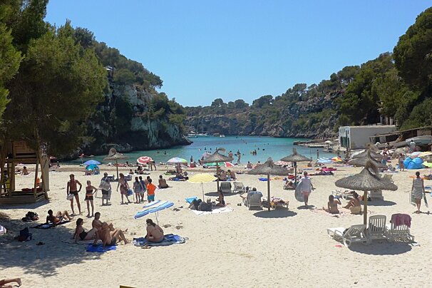 lots of parasols and people sunbathing on the beach
