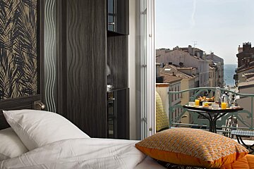 A hotel room with a balcony and a view of the city