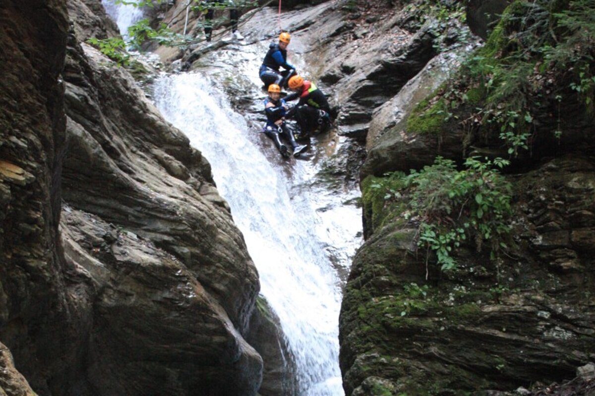 three canyoneers dropping into a river