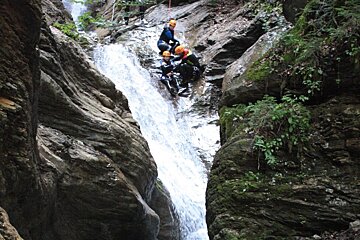 three canyoneers dropping into a river