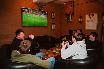 A group of men are watching a soccer game on a television