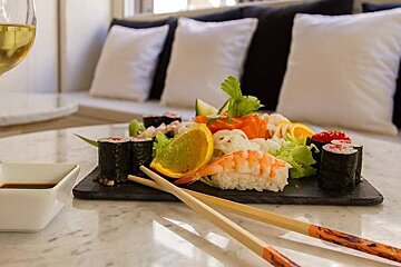 sushi and white wine with some chop sticks
