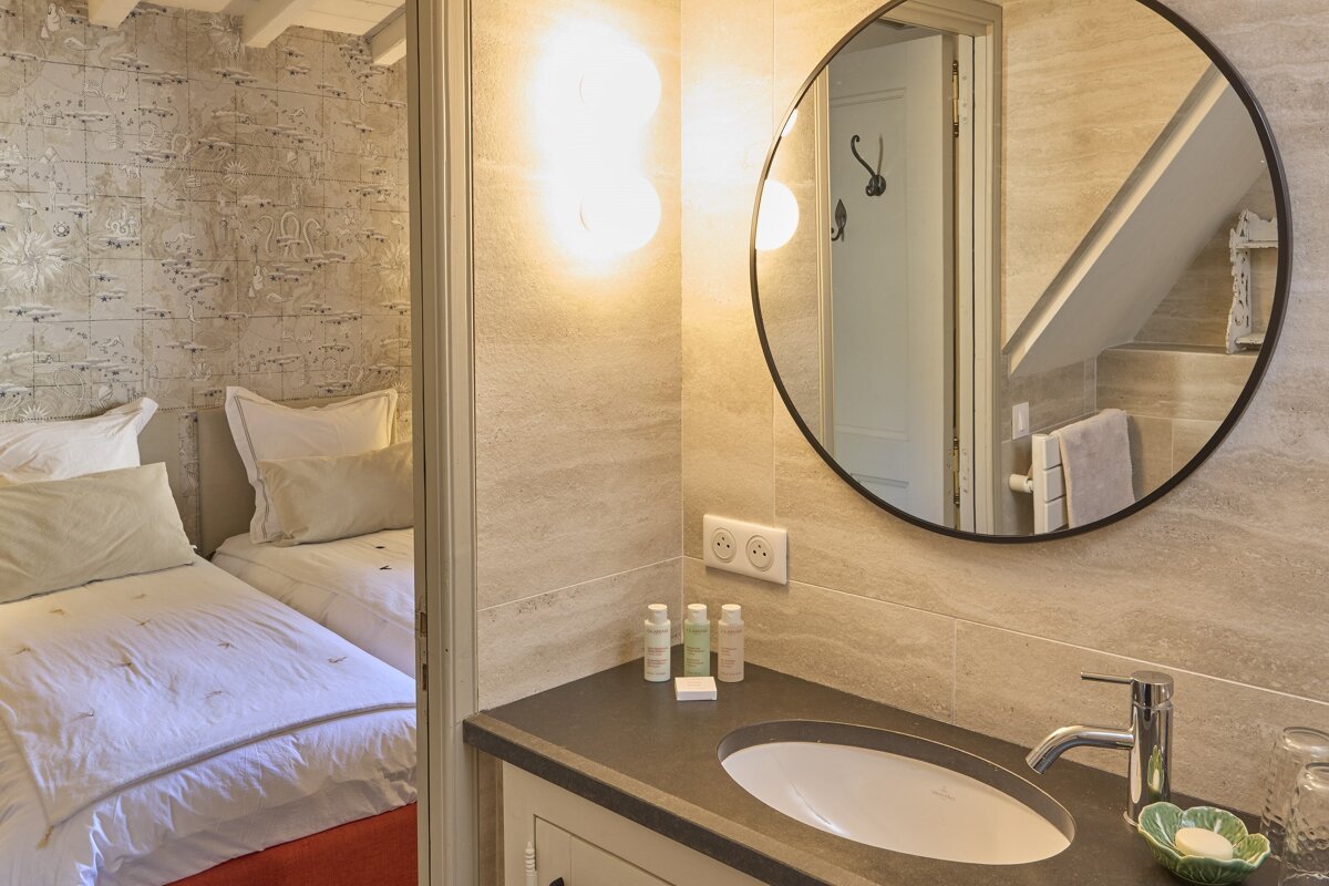 A bathroom with a round mirror and a sink