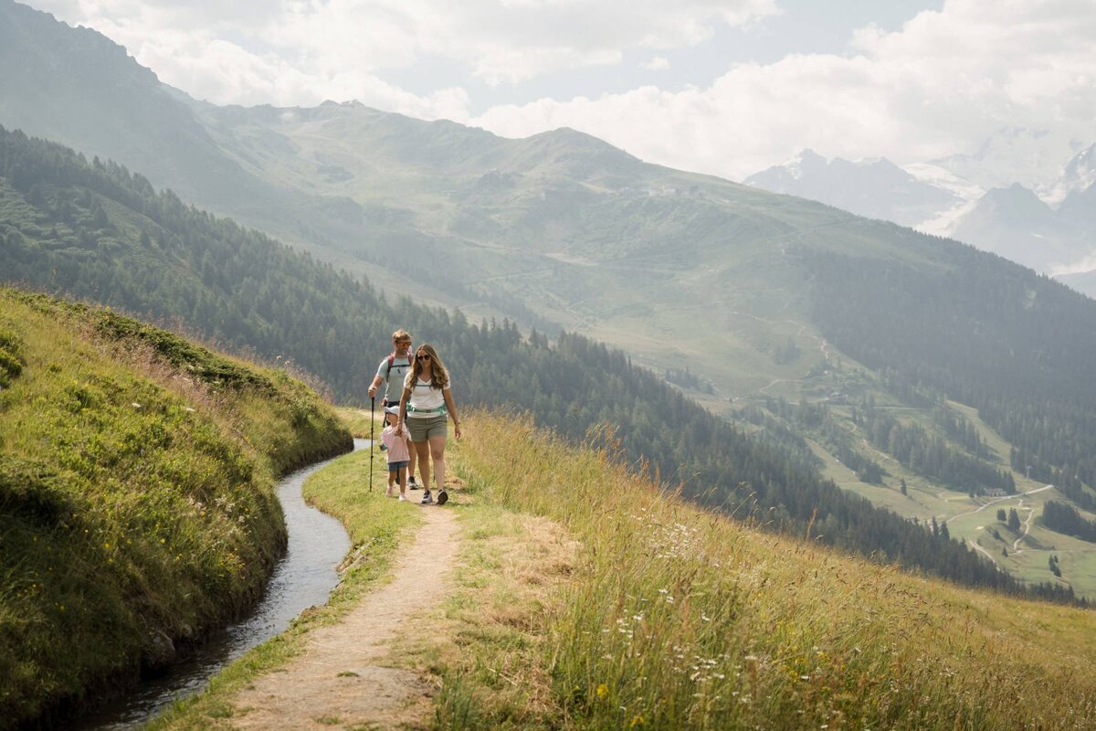 A woman and two children are walking down a path in the mountains